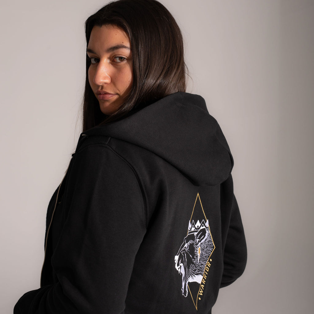 Wild Warrior zip-up hoodie with fierce lioness embroidery. Image view from the back with embroidery detail, model looking over her shoulder.